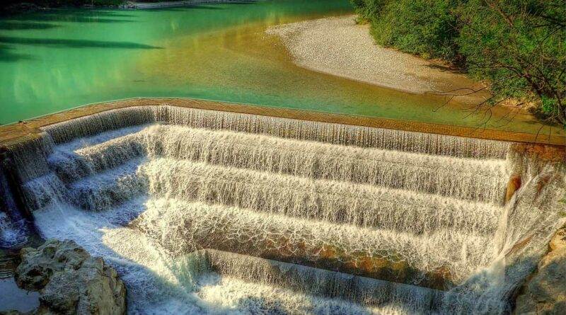 Ein malerischer Damm, über den Wasser strömt, ideal zum Wandern in Deutschland.
