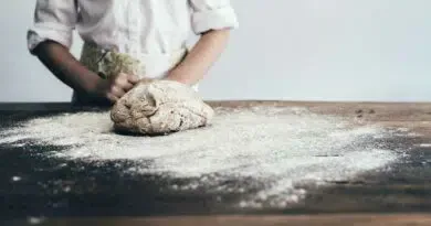 Ein Mädchen knetet Teig auf einem Holztisch, während es Brot backt.