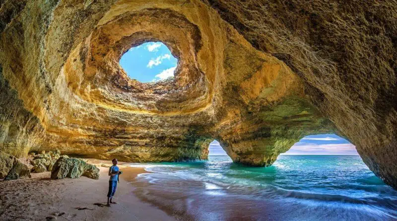 Eine Person, die einen Portugal-Urlaub in einer Höhle am Strand erlebt.