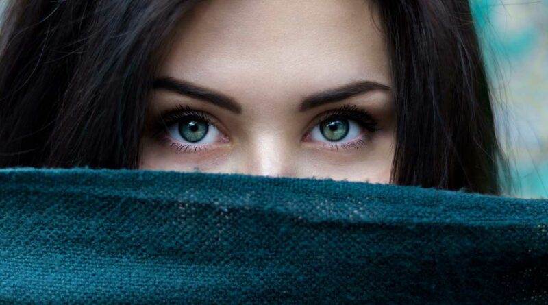 Eine Frau mit grünen Augen schaut aus einem Schal hervor.