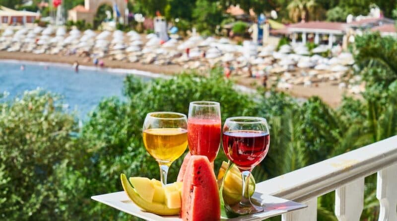 Zwei Gläser Wassermelonensaft und Obst auf einem Balkon mit Blick auf den Strand.