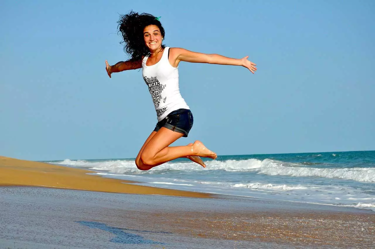 Eine Frau springt am Strand in die Luft.