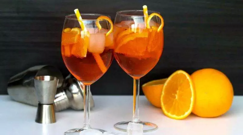 Zwei Gläser Cocktail mit Orangenscheiben und Eis.