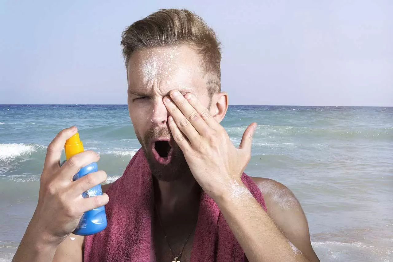 Ein Mann trägt Sonnenschutz auf seinem Gesicht am Strand auf.
