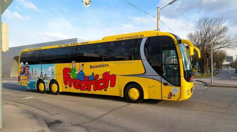 Ein gelber Bus fährt die Straße entlang, Anbieter Busreisen.