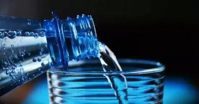 Eine Flasche Wasser wird in ein Glas gegossen.