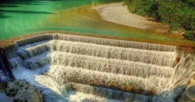 Ein malerischer Damm, über den Wasser strömt, ideal zum Wandern in Deutschland.