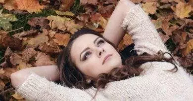 Eine Frau, die im Herbstmode mit den Herbstblättern verschmilzt.