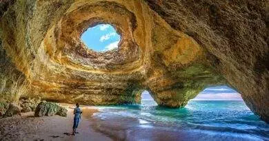 Eine Person, die einen Portugal-Urlaub in einer Höhle am Strand erlebt.