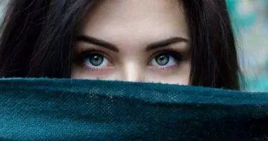 Eine Frau mit grünen Augen schaut aus einem Schal hervor.