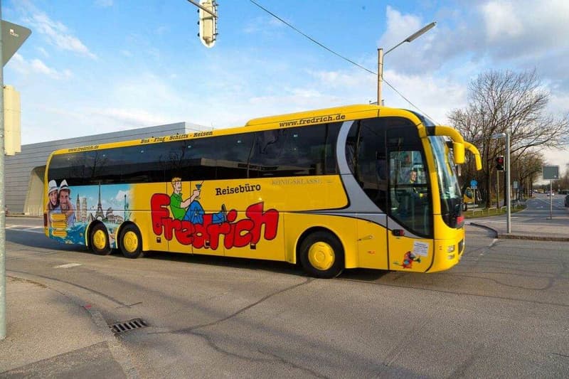 Ein gelber Bus fährt die Straße entlang, Anbieter Busreisen.
