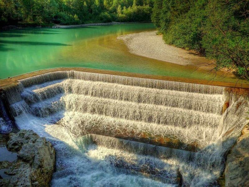 Ein malerischer Damm, über den Wasser strömt, ideal zum Wandern in Deutschland.