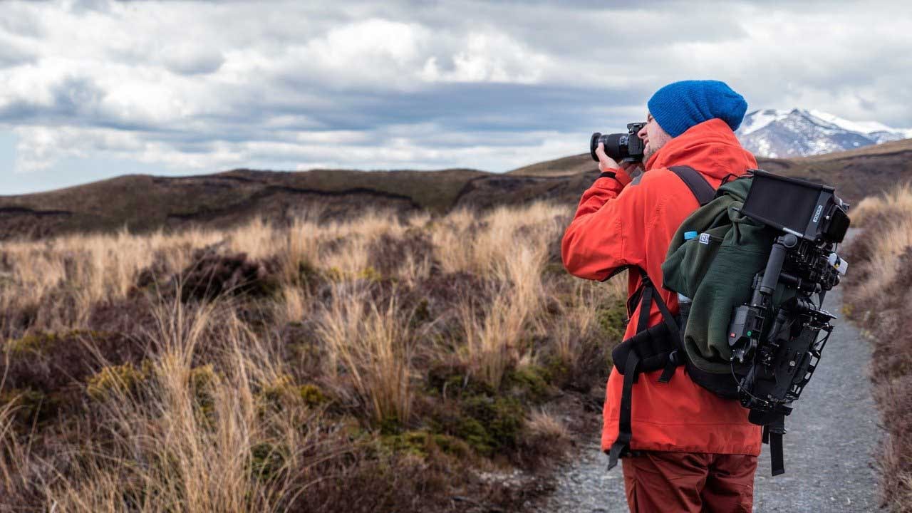 Ein Mann mit Rucksack fotografiert einen Berg.
